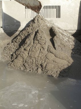 Dışarıdaki beton duvarın yanında duran büyük ıslak kum yığını