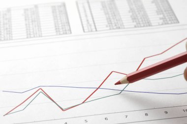 Finans grafikleri ve sayısal verileri inceleyen iş adamlarının yakın çekim görüntüleri, yatırım ve mali analizleri vurguluyor