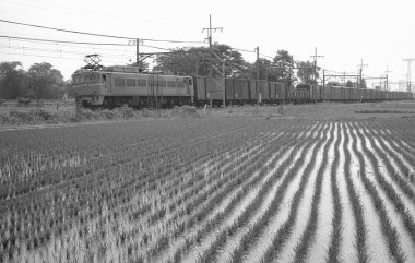 Tren raylarında giden bir trenin siyah beyaz fotoğrafı..