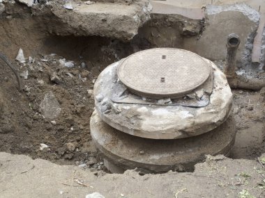 Kazılmış alan büyük beton rögar kapağını gösteriyor.