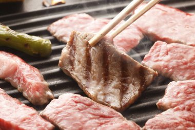 Et parçalarını ızgarada çeviriyor yemek çubukları, lezzetli barbekü çubukları kullanıyor.