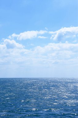 Mavi deniz ve gökyüzü beyaz bulutlarla