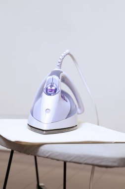 Gri arkaplandaki beyaz ütü tahtasında ütü.