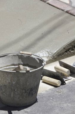 Beton kaldırım çalışması sırasında malaların yanında dinlenen çimento kovası.