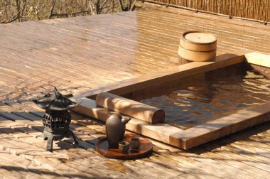 Tahta kaplama sıcak bahar banyosu çay setinin yanındaki güneş ışığını yansıtıyor.