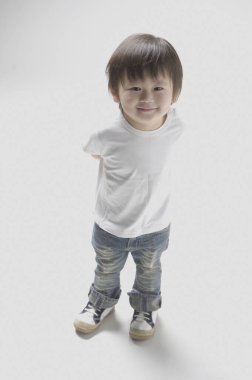 Beyaz arka planda Asyalı küçük çocuk stüdyoda poz veriyor.