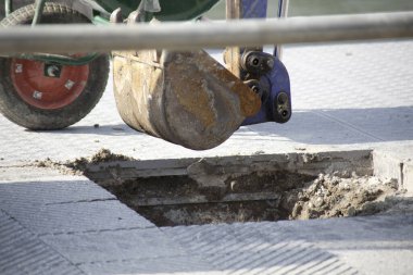 Kazıcı büyük dikdörtgen deliğin yanında beton yüzey kazıyor