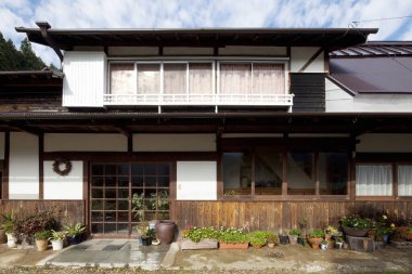 Geleneksel Japon evi dış yüzeyinde ahşap duvarlar, sürgülü kapılar ve saksılar var.