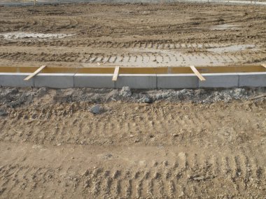 Beton kaldırım kenarındaki lastik izlerini gösteren yeni derecelendirilmiş toprak.