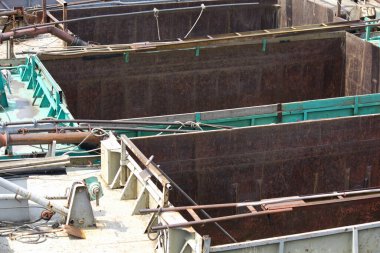 Dışarıda yeşil korkuluklarla çevrili büyük endüstriyel metal tanklar.