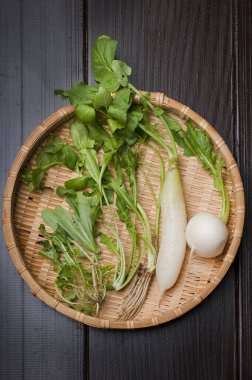 Taze bahar turpu ve siyah tabakta yeşil yapraklar.