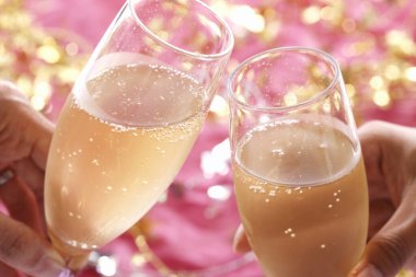 Arka planda şenlik dekoru olan şampanya kadehlerini tutan ellerin görüntüsünü kapat.