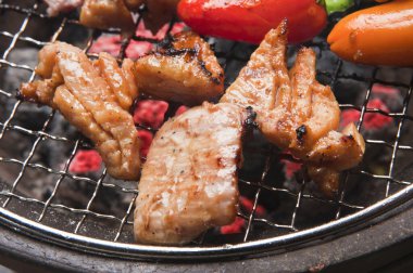 Japon restoranındaki ızgarada et ve sebze pişiren kişinin yakın çekim görüntüsü 