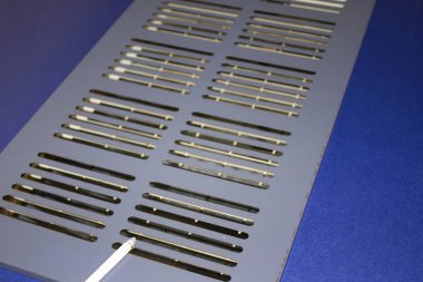 Metal menfez kapağı mavi yüzey arka planında dinleniyor