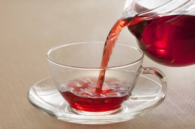 Sıcak kırmızı çayı cam fincana dök.