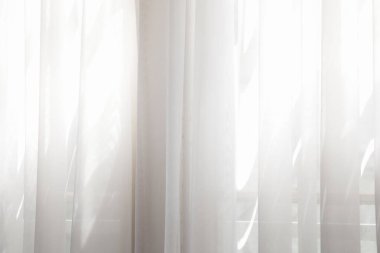 Penceresinden güneş ışığı geçen beyaz perdeler 