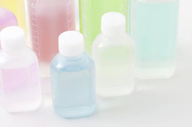 Işık arkaplanındaki renkli plastik sıvı şişelerinin yakın plan görüntüsü       