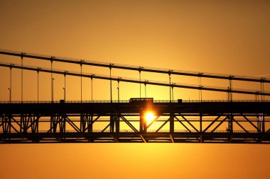 Gün batımında şehirde bir köprünün silueti. 