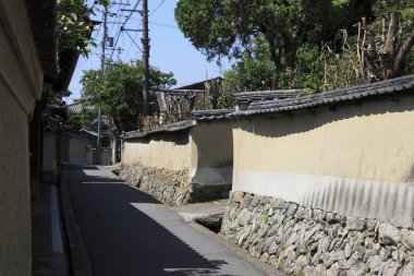 Taş duvarlar ve yeşilliklerle dolu geleneksel Japon sokak araları.