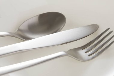 Beyaz arka planda gümüş kaşık, bıçak ve çatal