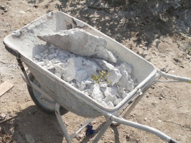 El arabası yerde gri inşaat malzemeleriyle dolu.