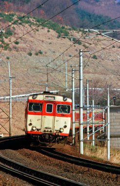 Bir tren dağlardan geçen tren rayları boyunca ilerliyor.
