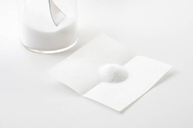 Boş beyaz bir sayfa kağıt ve açık gri arkaplanda bir kavanoz şeker..