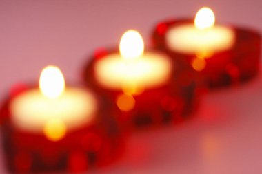 Kırmızı kalp şeklinde şamdanlarla mum yakmak.