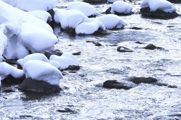 一条被雪覆盖着岩石和水的小河 — 图库照片