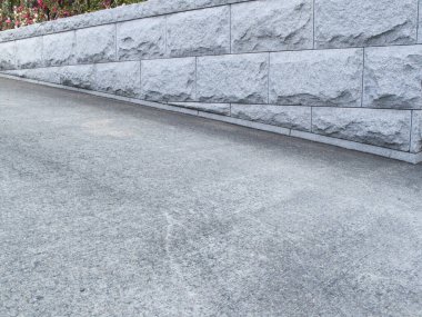 Taş duvarın yanında çiçekli gri beton yüzey