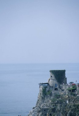 Sakin mavi okyanus sularına bakan antik taş kule
