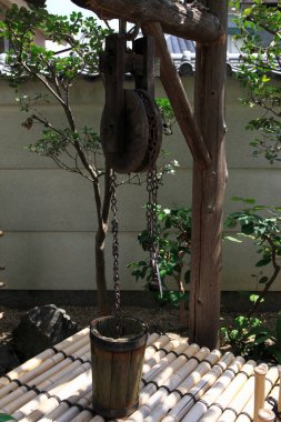 Tahta makara sistemi dışarıda bambu platformunun üzerinde kova tutuyor.