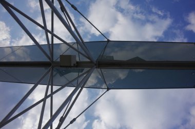 Mavi gökyüzüne karşı cam yapıya bakıyorum.