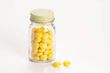 Sarı haplarla dolu cam kavanoz.