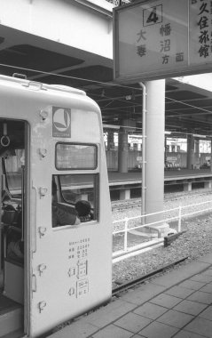 Halka açık bir istasyonda yolcu treni. Siyah beyaz fotoğraf.