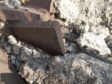 Büyük paslı metal kirişleri çevreleyen sert beton molozlar.