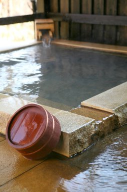 Geleneksel Japon sıcak bahar banyosunun yanında dinlenen tahta kova.