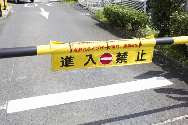 Sarı bariyer Japon uyarı işareti ile dar yolu kapatıyor.