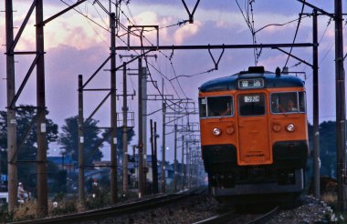 Tren Japonya 'da gün batımında demiryolunda hareket ediyor.