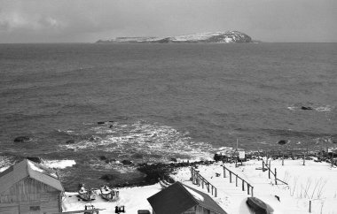 Uzak bir adaya bakan karlı kıyı köyü