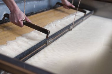 Eller çerçeveyi sıvı yüzeyin üstünde tutuyor