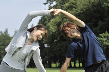 Genç çift parkta egzersiz yapıyor. 