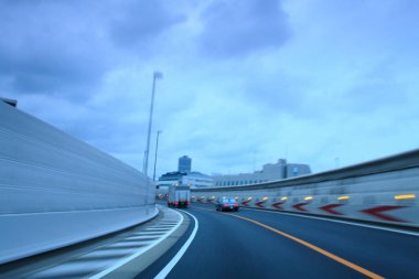 Günbatımında modern şehirde otoyolda giden arabaların hareket bulanık görüntüsü