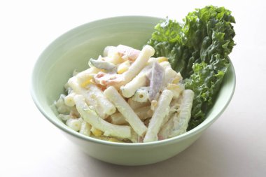 Yeşil kasede servis edilen kremalı makarna salatası.