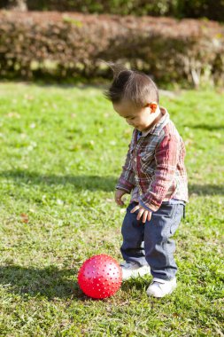 Parkta topla oynayan tatlı bir bebek.