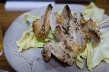 Kızarmış tavuk şişleri taze lahana üzerinde dinleniyor.