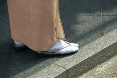 Şehir caddesinde takım elbiseli ve terlikli bir kadın. 