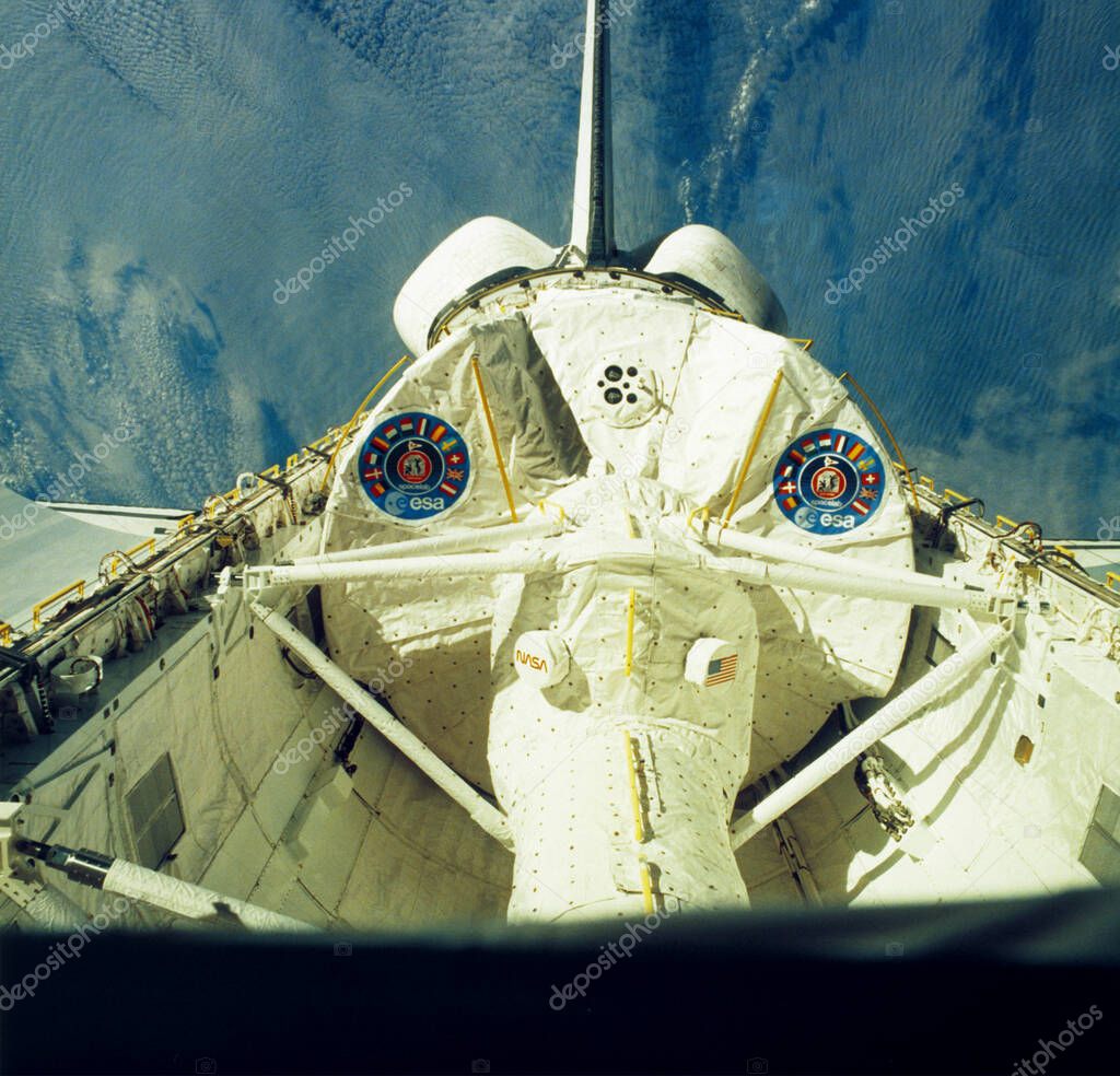 The Space Shuttle payload bay is shown open in orbit, with Earth's blue atmosphere visible beyond.