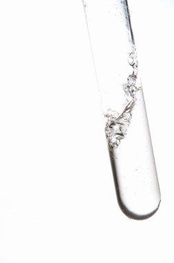 Beyaz zemin üzerinde sıvı bulunan laboratuvar test tüpünün yakın görüntüsü                  