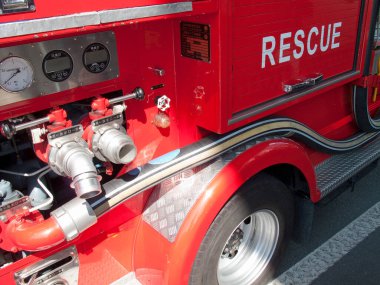 Kurtarma ekipmanları ve hortumları gösteren kırmızı itfaiye aracının yakınına.